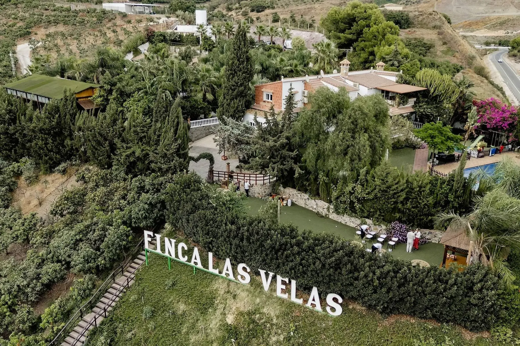 Vista aérea de la finca: las letras blancas «Finca Las Velas» sobre un seto, y los jardines y la casa detrás