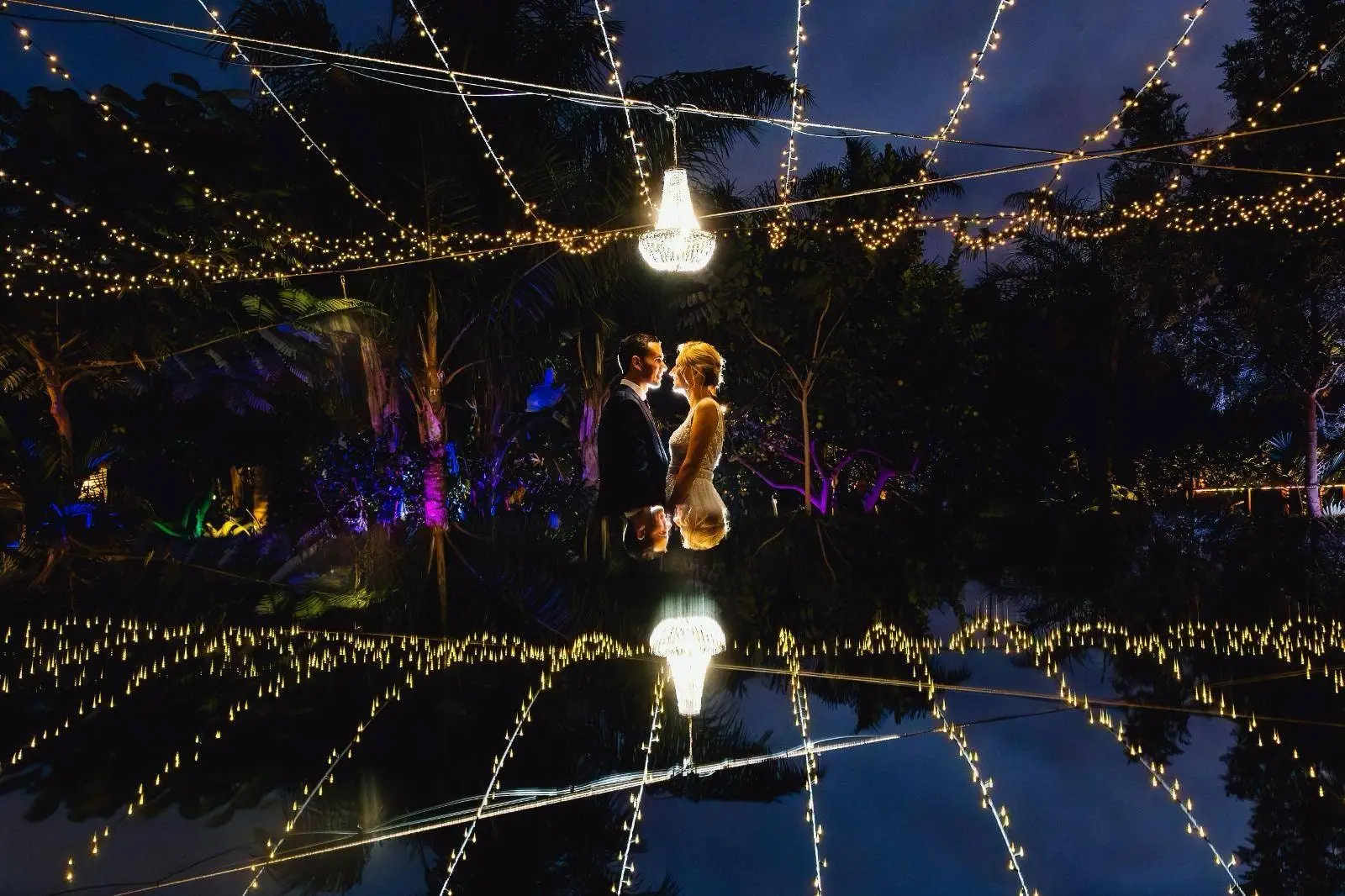 Una pareja baila de noche, con las luces del jardín reflejadas en el suelo