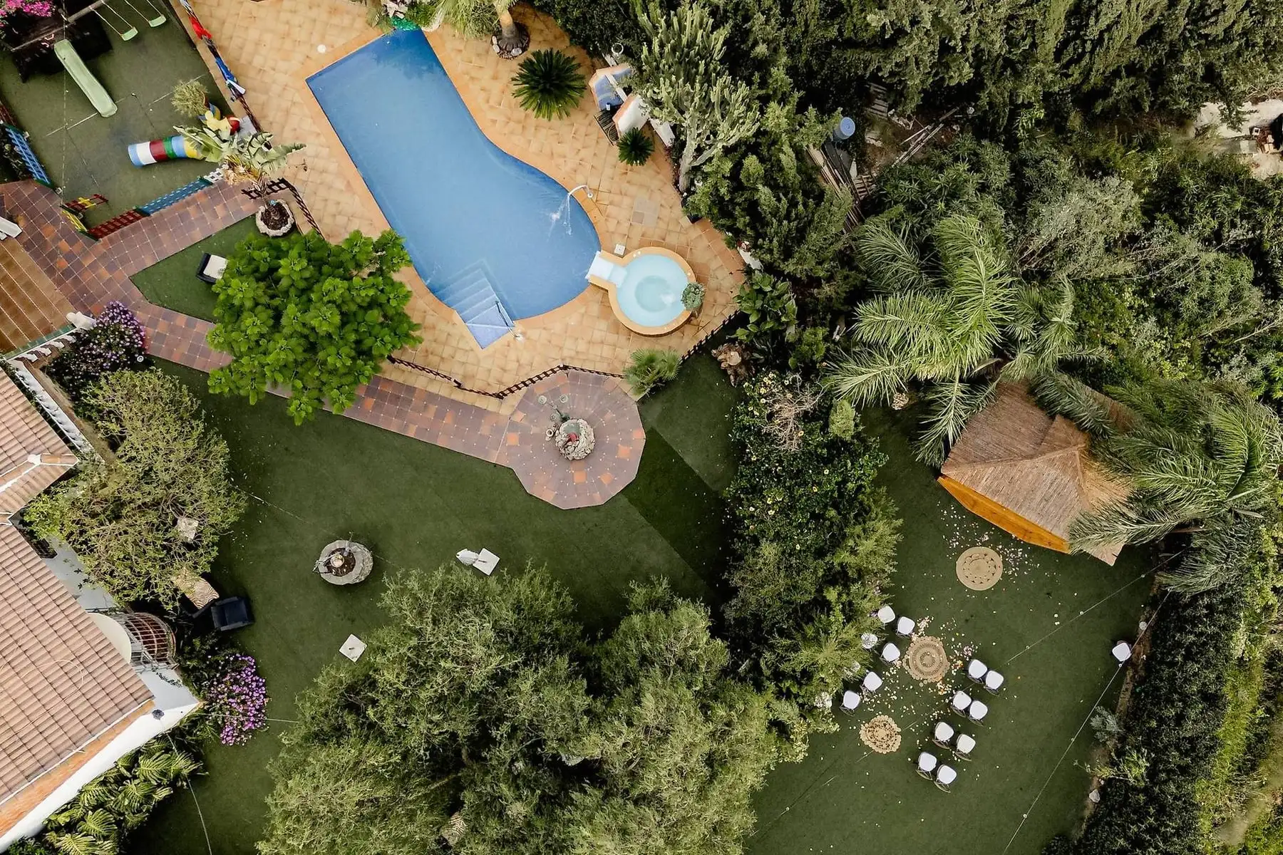 La piscina y el jacuzzi vistos desde arriba, entre jardín y césped